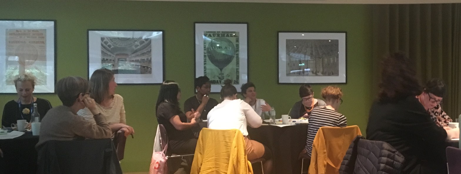 Women sit around a table talking and listening to each other.